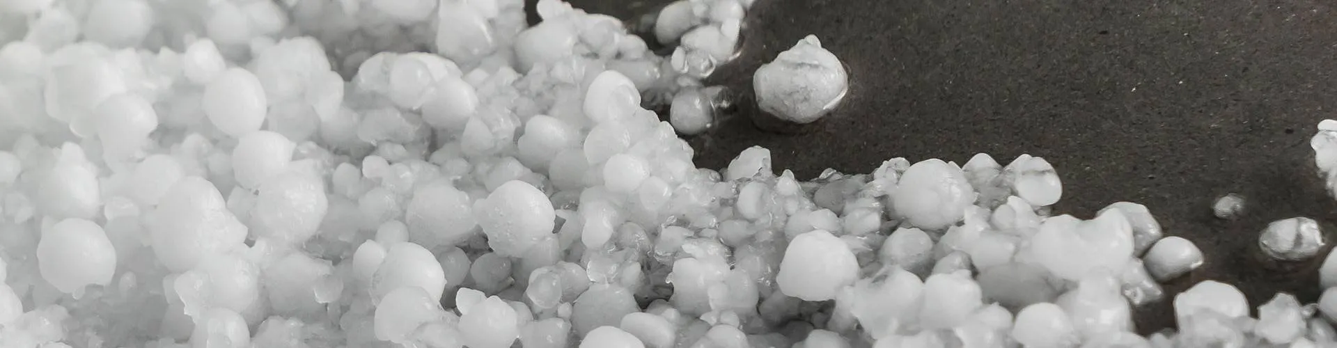 Hailstones piled on a dark roof surface
