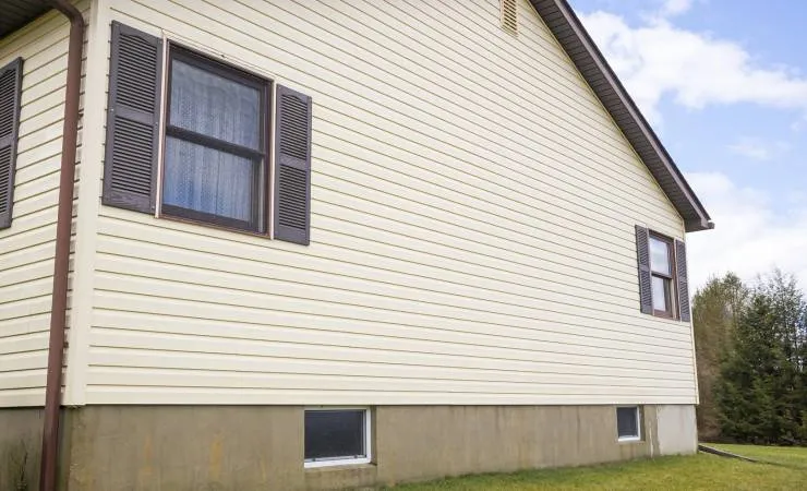 House with cream vinyl siding and dark window shutters