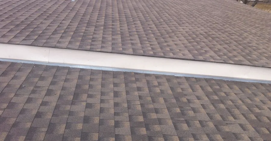Brown shingle roof with flashing between two roof sections