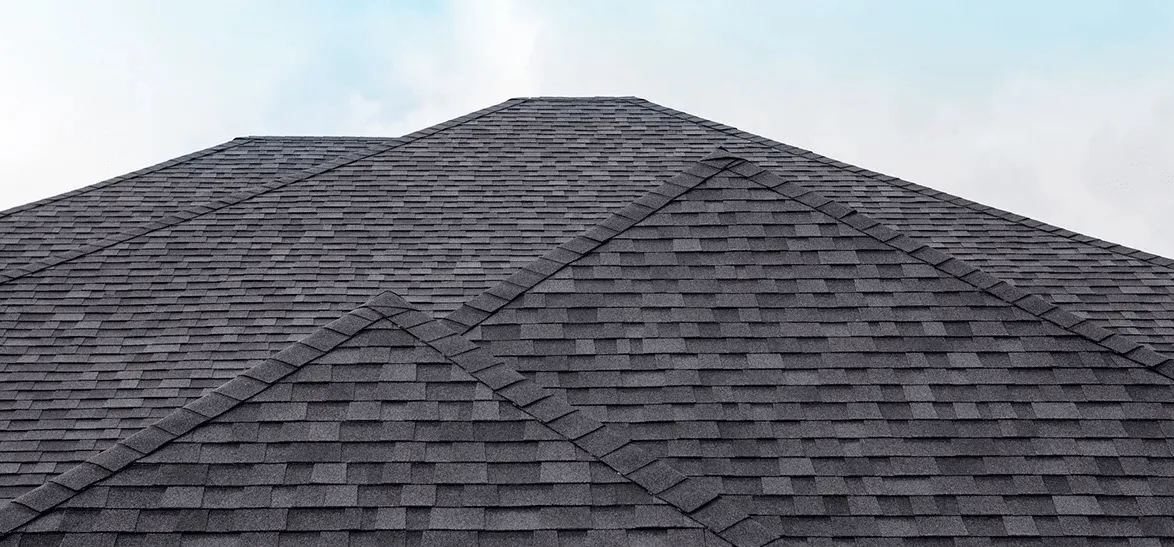 Dark shingle hip roof against the sky